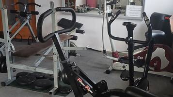 Une salle de sport équipée de divers appareils d’exercice, notamment un banc, des appareils de musculation et des appareils de cardio.