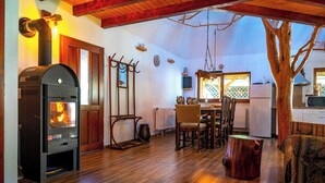 Un salón acogedor con una chimenea de leña, muebles de madera y un tronco de árbol rústico como pieza central.