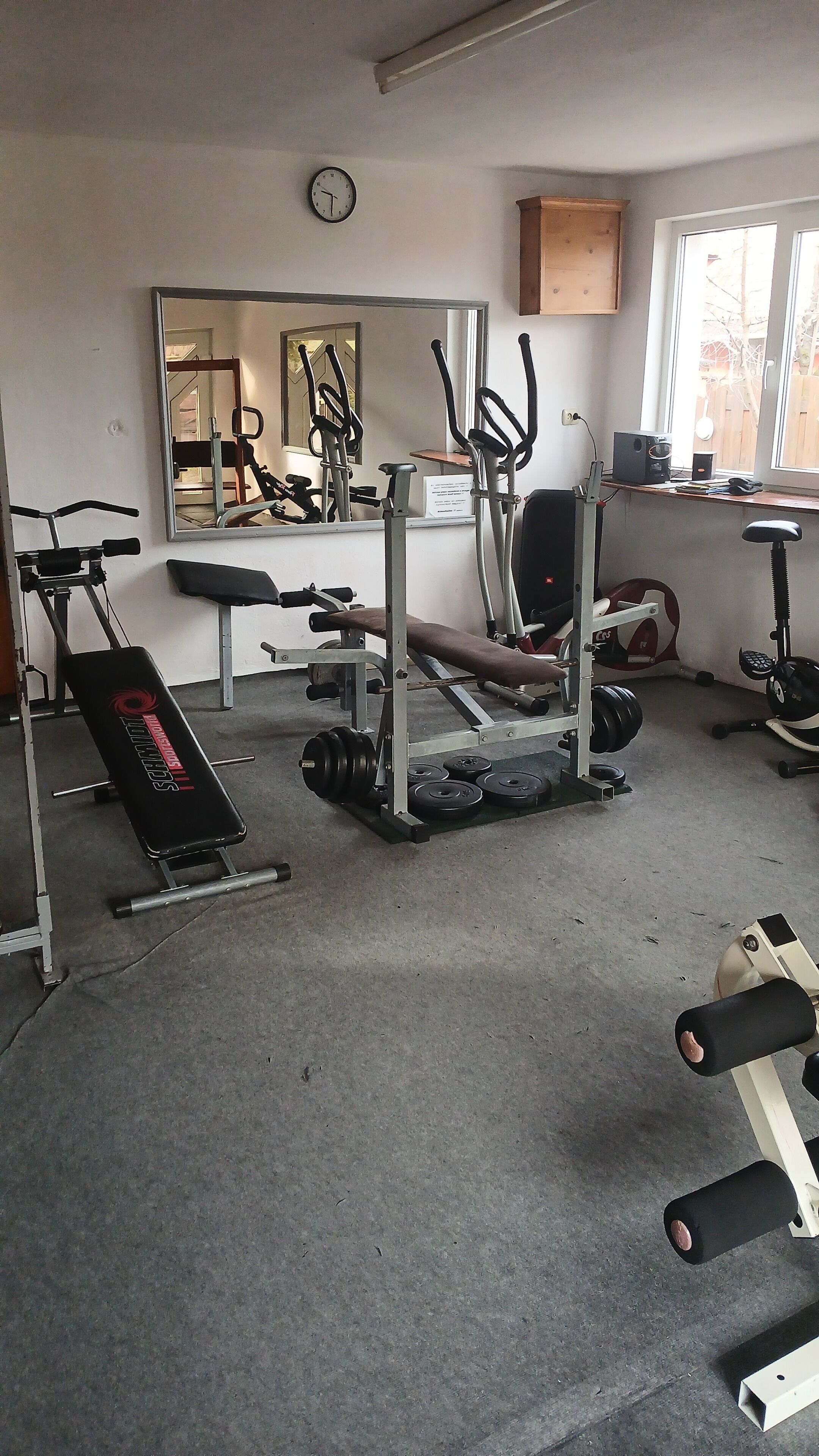 Un gimnasio con equipo de ejercicio, un espejo grande y una ventana que ofrece vistas al exterior.