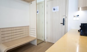 Une salle de bain moderne avec un banc en bois, une douche en verre et des toilettes séparées par un écran.