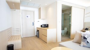 A modern hotel room with a kitchenette, a glass-enclosed shower, a sofa, and a small table. - 2314 1BR Wyndham Naithon (Sa Khu)