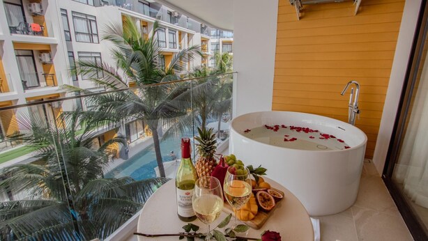 A balcony with a bathtub filled with rose petals, a bottle of wine, and a fruit platter. - 2314 1BR Wyndham Naithon (Sa Khu)