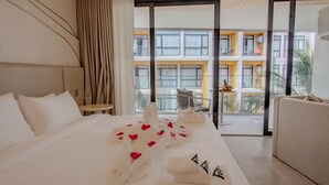 A hotel room with a bed, a small table, and a balcony with a view of a building. - 2314 1BR Wyndham Naithon (Sa Khu)