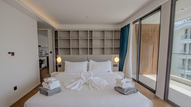 Une chambre d’hôtel moderne dotée d’un grand lit, d’une armoire intégrée, d’une salle de bain et offrant une vue sur la ville.