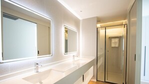 Un bagno moderno con un ampio lavabo, due specchi e una cabina doccia in vetro.