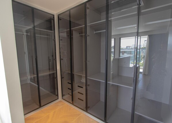 A room with a large walk-in closet featuring sliding glass doors and multiple shelves. - 189/267 3BR Beachfront Pool View (Choeng Thale)
