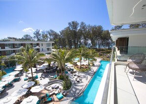 Et resortområde med swimmingpool, liggestole, parasoller og palmer.