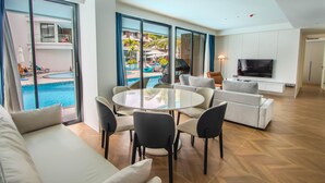 A modern living room with a pool view, a dining area, and a TV. - 189/222 3BR Beachfront Luxe Pool Access (Choeng Thale)