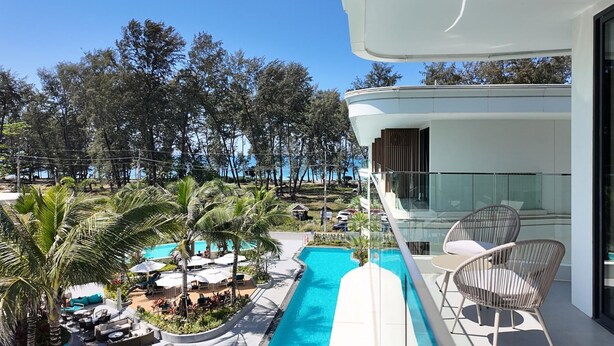 A modern hotel with a pool area, outdoor seating, and a view of the surrounding trees. - 189/222 3BR Beachfront Luxe Pool Access (Choeng Thale)