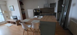 Eine moderne Küche mit Essbereich, ausgestattet mit einem Holztisch, weißen Stühlen, einer Mikrowelle und einem Kühlschrank.