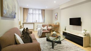 Ein modernes Wohnzimmer mit einer Couch, einem Couchtisch, einem Fernseher und einem Fenster mit Vorhängen.