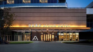 A modern hotel with a prominent entrance, a large illuminated sign, and a curved facade. - Atour Hotel (Wuxi)