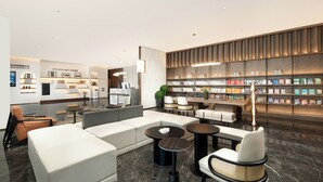A modern hotel lobby with a seating area, a reception desk, and a bookshelf filled with books. - Atour Hotel (Wuxi)