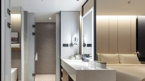 A modern bathroom with a glass shower enclosure, a large mirror, and a vanity with a sink and towel rack. - Atour Hotel (Wuxi)