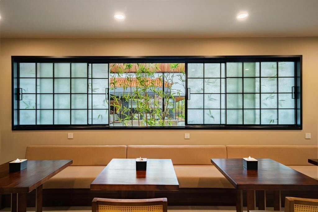 A room with a large window, wooden furniture, and a view of greenery outside.