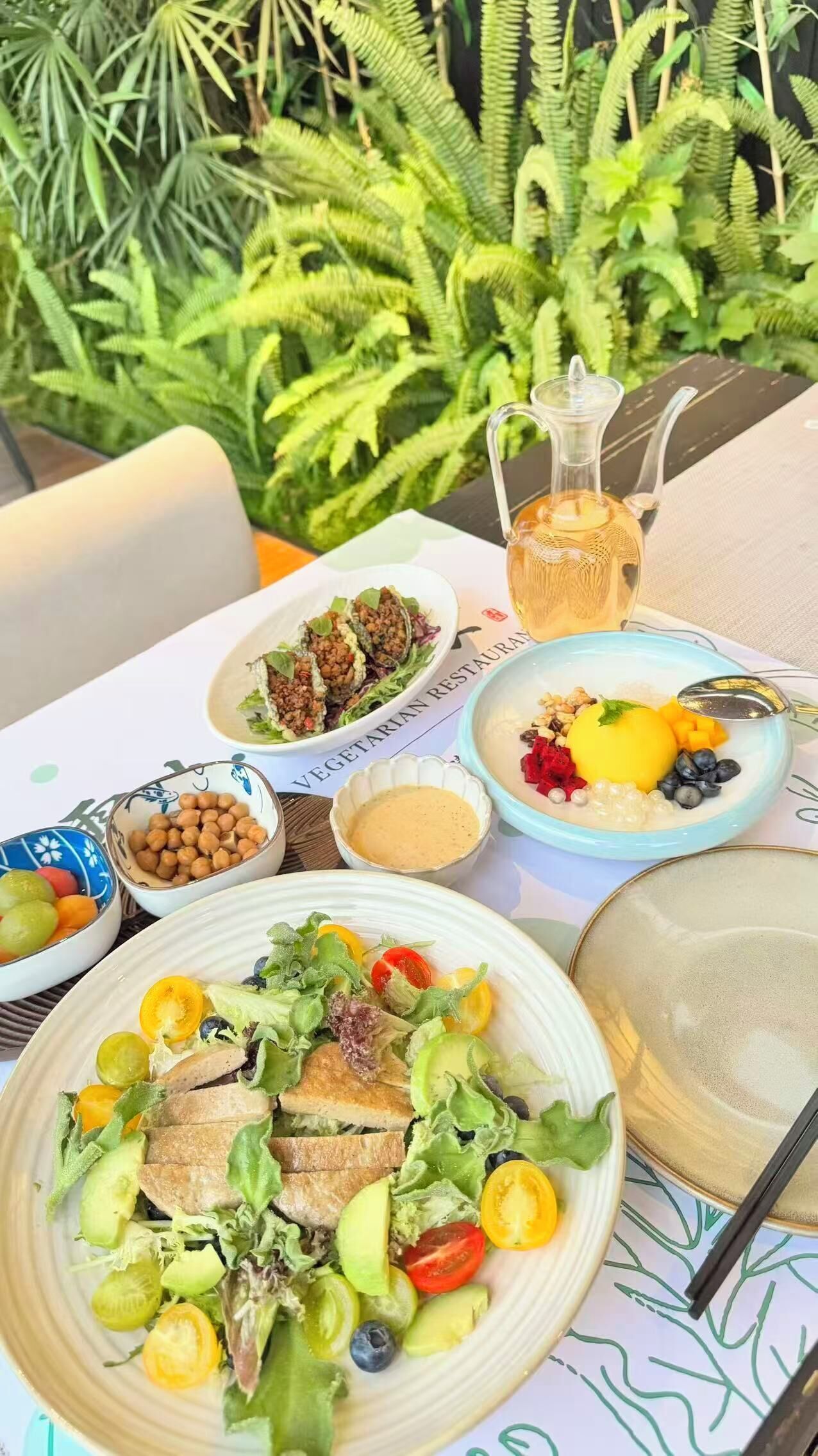 A table set with various dishes including a salad, a fruit bowl, and a bowl of chickpeas.