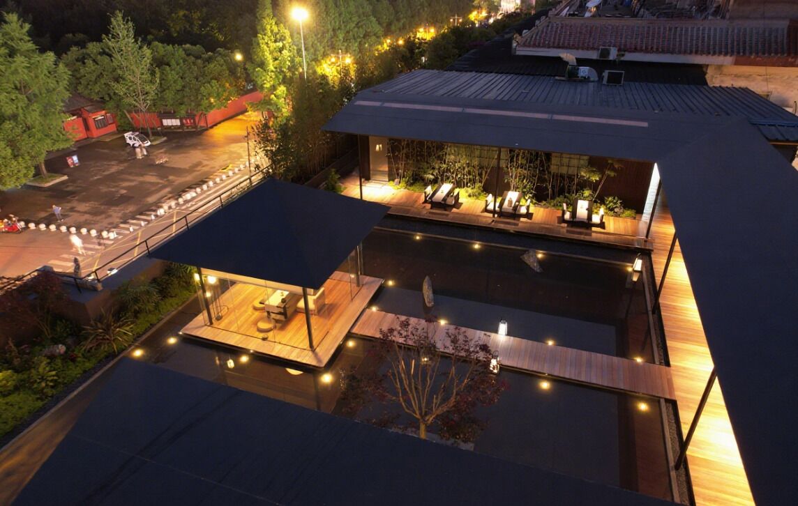 A rooftop pool area with lounge chairs and a wooden deck.