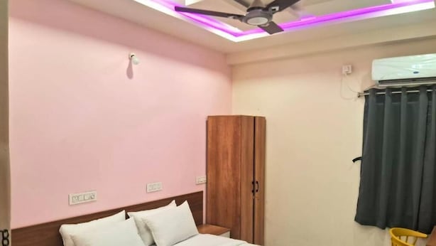 Une chambre à coucher comprenant un lit, une armoire, un ventilateur de plafond et un appareil de climatisation.