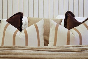 A bed with striped pillows and a fluffy blanket. - Understated Luxury Flat in Mayfair (London)