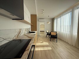 Una cocina moderna con encimera de mármol, estufa integrada y comedor con mesa y sillas.