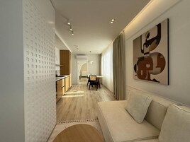 A modern interior with a sofa, abstract art, and a kitchen area.