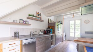 A modern kitchen with stainless steel appliances, wooden cabinets, and a built-in dishwasher. - Charming Family Holiday Home with Private Terrace and Garden (Le Grand-Village-Plage)