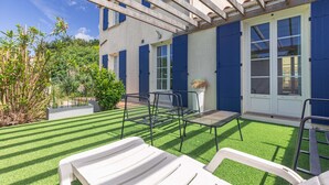 A patio with artificial grass, outdoor furniture, and a pergola structure. - Charming Family Holiday Home with Private Terrace and Garden (Le Grand-Village-Plage)