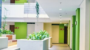 Un pasillo moderno de hotel con paredes verdes, puertas numeradas e interiores plantas.