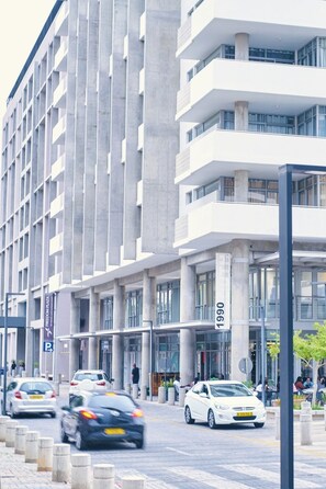 A modern building with a prominent '1990' sign, multiple floors, and a parking area. - City Apartments at Freedom Plaza (Windhoek)