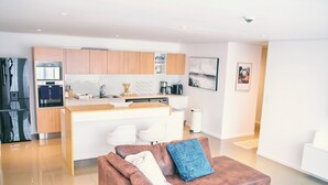 Una cocina moderna con armarios de madera, una isla central y una zona de comedor con sillas blancas.