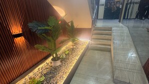 Een moderne binnenruimte met een houten wand, een kleine plantenbak met planten en een betegelde vloer.