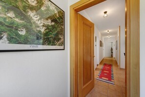 A hallway with a wooden door, a framed map, and a red carpet.