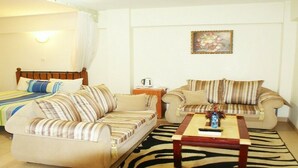 A living room with striped sofas, a wooden coffee table, and a zebra-patterned rug. - Meru Paramount Hotel (Meru)