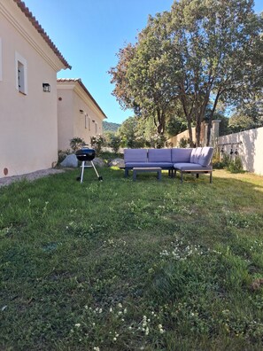 A patio with a grill, a sofa, and a tree. - 70 m² air-conditioned mini-villa with garden 5 minutes from beaches. (Serra-di-Ferro)