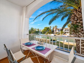 A balcony with a table set for two, overlooking a body of water and a residential area. - 0146-PATTAYA Apartment with canal view (Empuriabrava)