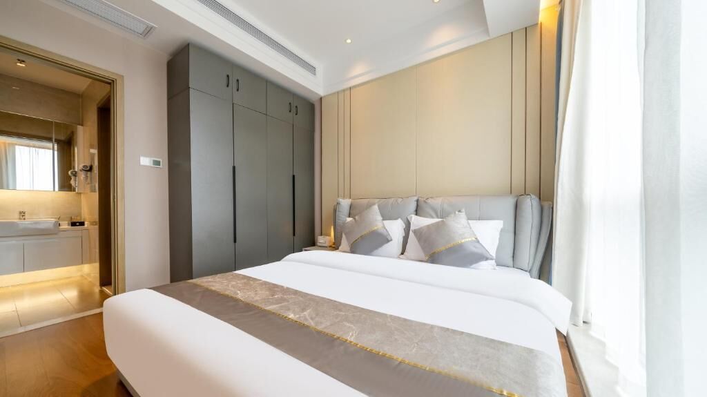 Una habitación de hotel moderna con una cama grande, un armario empotrado y un baño con tocador.