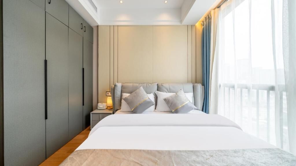 Ein modernes Hotelzimmer mit einem großen Bett, einem Nachttisch und einem Kleiderschrank.