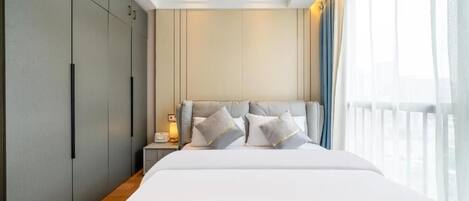Ein modernes Hotelzimmer mit einem großen Bett, einem Nachttisch und einem Kleiderschrank.