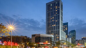 A modern high-rise building with a glass facade, surrounded by other buildings and street lights. - Youyue High-Rise Apartment - Chunxi Road (Chengdu)