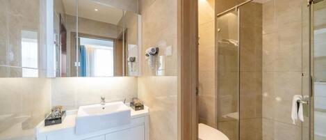 A modern bathroom with a glass shower enclosure, a white sink, and a large mirror.