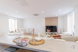 Ein modernes Wohnzimmer mit Essbereich, Fernseher und einer Wandpaneele aus Holz.