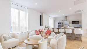 Een moderne woonkamer met een zithoek, een salontafel en een keukenbar met barkrukken.