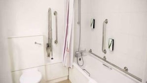 A bathroom with a white toilet, a shower with grab bars, and a glass-enclosed sink. - Coventry South (A45) (Coventry)