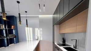A modern kitchen with a large island, dark cabinetry, and pendant lighting. - City Centre Penthouse  (Tirana)