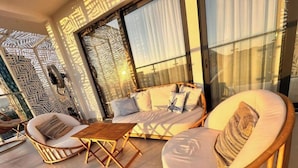 A balcony with wicker furniture, including a sofa and chairs, and a small wooden table. - City Centre Penthouse  (Tirana)