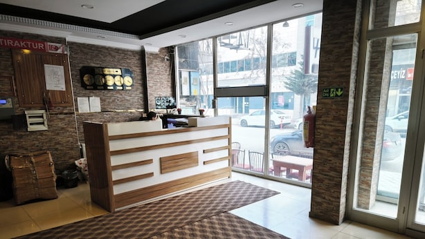 A hotel reception area with a reception desk, a clock, and a view of the street outside. - Yılay Otel (Igdir)