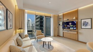 Een moderne woonkamer met een bank, fauteuils, een salontafel, een televisie en uitzicht op de stad door grote ramen.