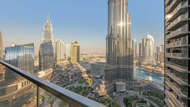Een hoog gebouw met een gebogen gevel en een glazen buitenkant, omgeven door andere moderne wolkenkrabbers en een rivier.