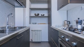 Een moderne keuken met een roestvrijstalen spoelbak, een inbouwfornuis en een koffiezetapparaat.