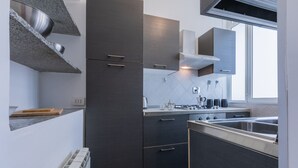 Een moderne keuken met donkere kastjes, roestvrijstalen apparatuur en een raam dat voor daglicht zorgt.